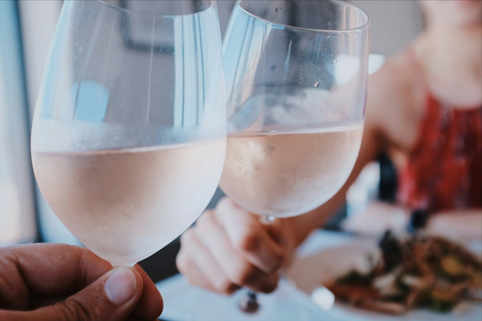 Zwei Gläser Wein beim Anstoßen an einem gedeckten Tisch